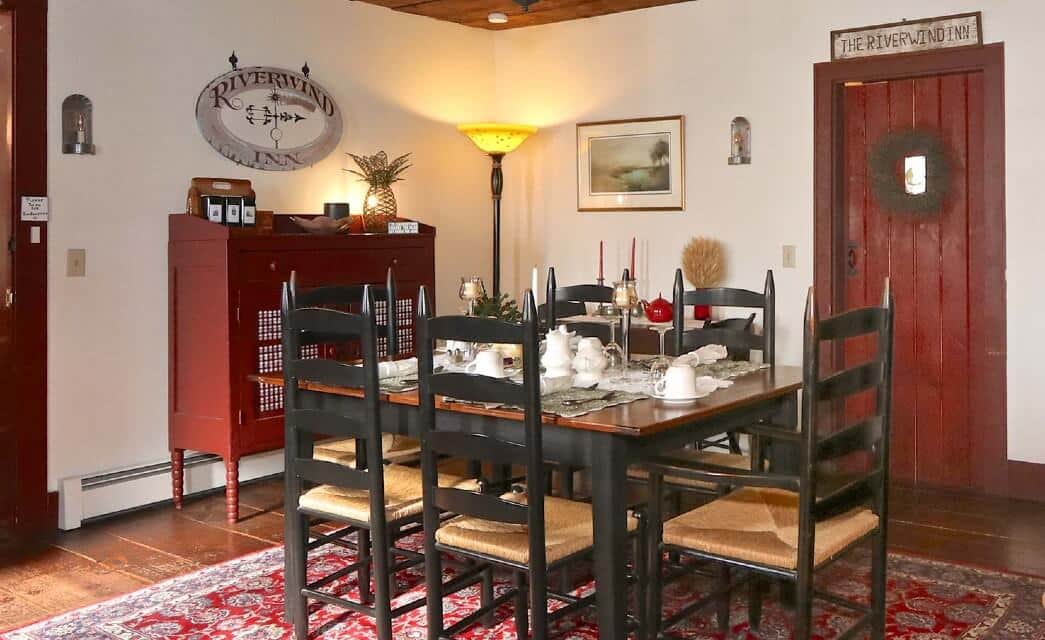 Dining room with black and brown table with six chairs, red hutch and red door
