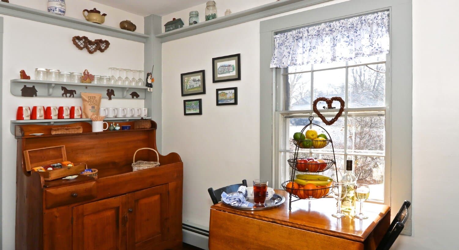Nook in a home with dropleaf table, two chairs and wooden hutch with coffee mugs