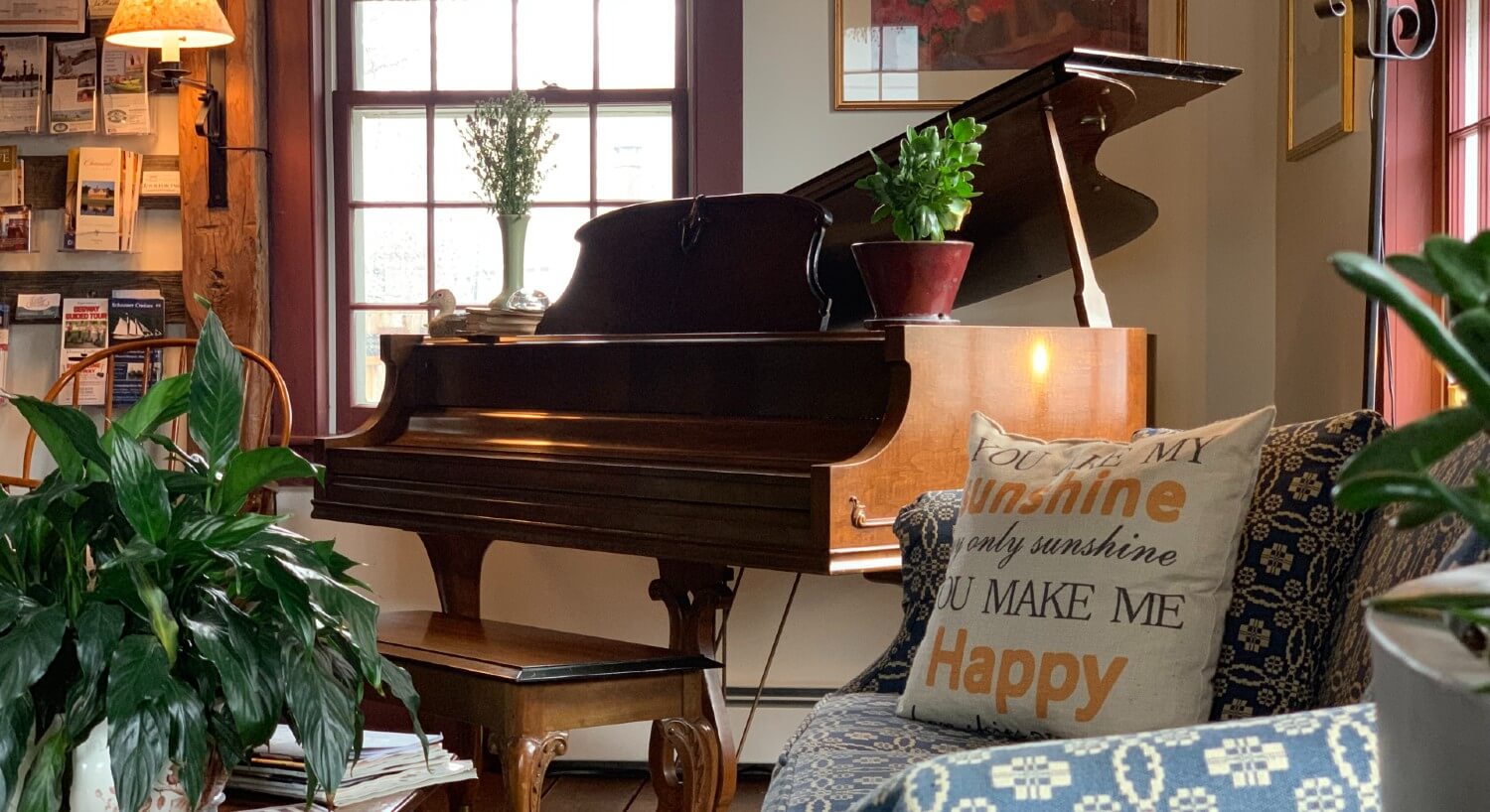 Beautiful brown piano in a corner by bright windows and floral couch