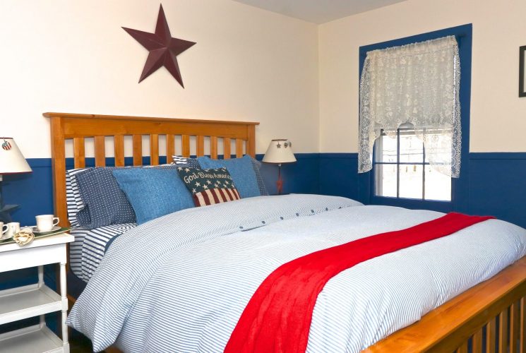 Red, white and blue themed bedroom with bed, white side tables and purple star decoration