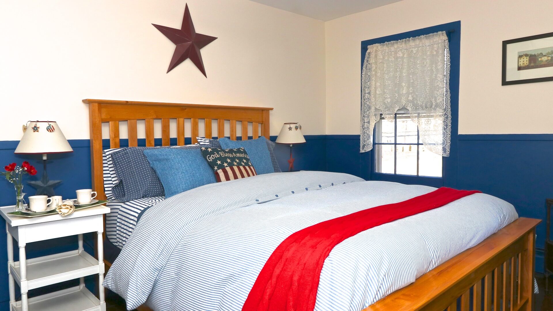 Red, white and blue themed bedroom with bed, white side tables and purple star decoration