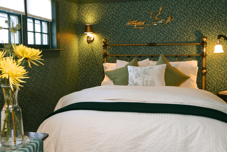 Green bedroom with queen bed, brass headboard, white and green bedding