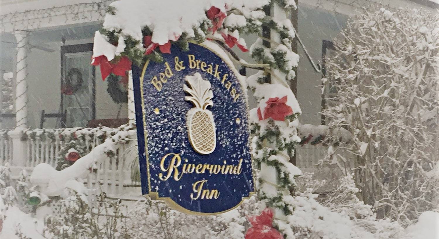 Blue oval sign for a bed and breakfast covered with freshly fallen snow