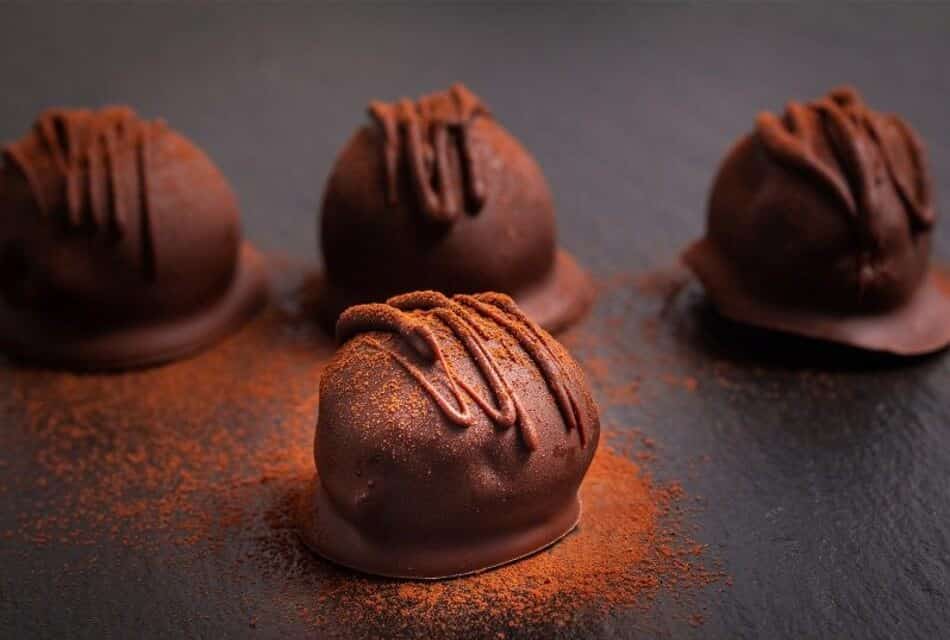 Four dark brown truffle chocolates dusted in cocoa powder